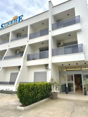 a white building with a sign on it at Sunrise Apart-Hotel in Ulcinj