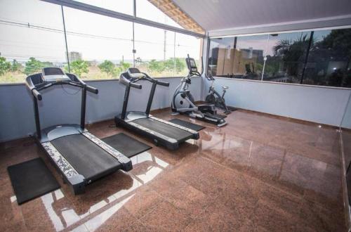 a gym with three tread machines in a room with windows at Flat Diroma Fiori in Caldas Novas