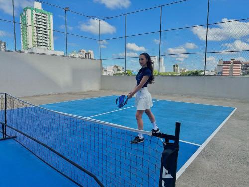 a woman holding a tennis racket on a tennis court at ApartDamani - Aptos por Temporada no centro in Foz do Iguaçu