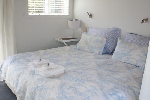a bed with a white comforter and pillows at Mangawhai Chalets in Mangawhai