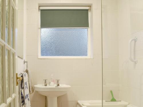 a bathroom with a sink and a toilet and a window at Flat 1 Garden View - Ukc4221 in Lowestoft