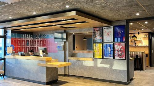 a restaurant with a woman sitting at a counter at ibis budget Avignon Centre in Avignon
