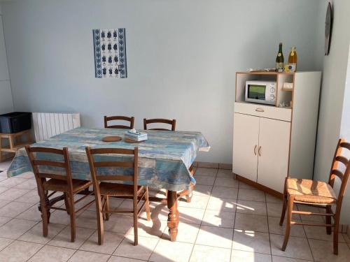 a kitchen with a table with chairs and a microwave at An Distro Pesketa in Penmarcʼh