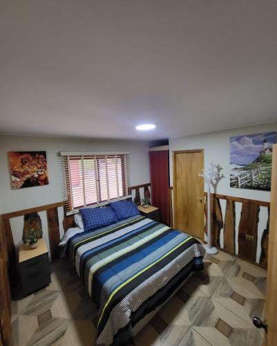 a bedroom with a bed with blue pillows and a window at Cabañas Torres Del Bosque in Pucón
