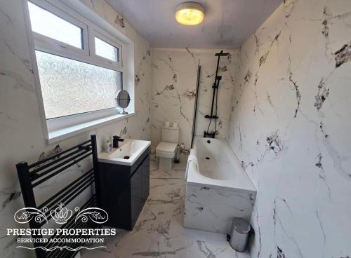 a white bathroom with a tub and a sink at 12 Romney Road by Prestige Properties SA in Barrow in Furness
