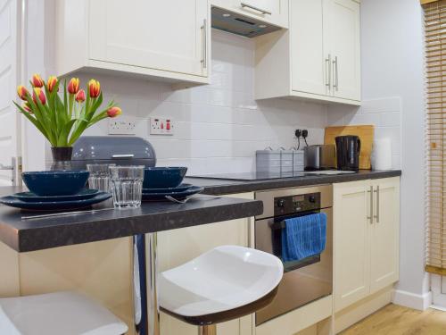 a kitchen with white cabinets and a black counter top at The Studio in Long Hanborough
