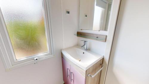 une salle de bain avec un lavabo et une fenêtre dans l'établissement Cottage Vendeen avec pisicines, à Saint-Jean-de-Monts