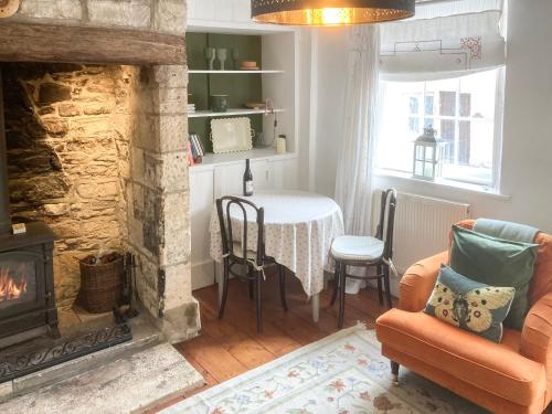 een woonkamer met open haard en een tafel bij Cenwulf Cottage in Winchcombe