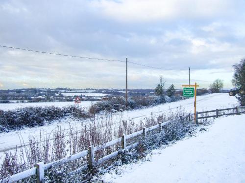 a snow covered road with a fence and a sign at The Granary - Uk47480 in Shuttington