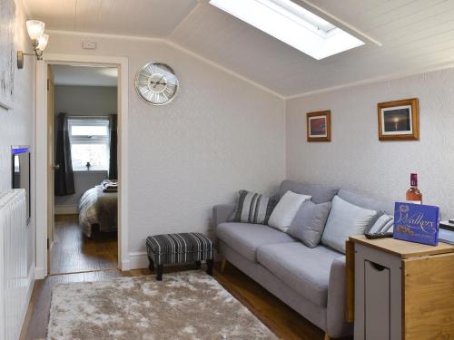 a living room with a couch and a clock on the wall at Cuillin View Apartment - Uk12529 in Arisaig