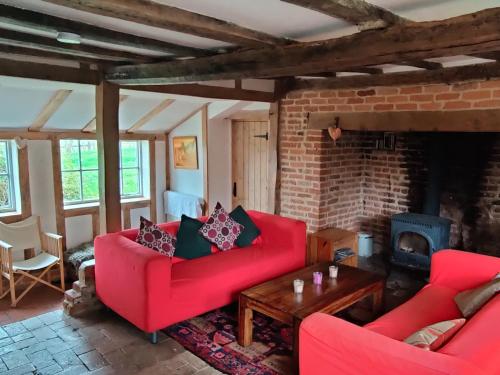 un soggiorno con divani rossi e camino di Burnt House Cottage a Barking