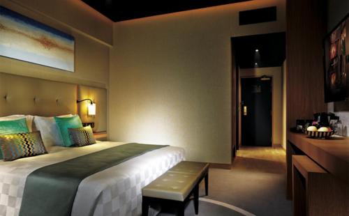 um quarto de hotel com uma cama grande e um banco em Resorts World Genting - Highlands Hotel em Genting Highlands