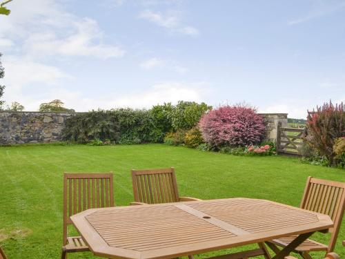 a wooden table and two chairs in a yard at Hume Orchard Steading in Hume