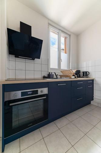 Il comprend une cuisine équipée d'une cuisinière et une télévision murale. dans l'établissement Le Desbrest - Appartement calme et lumineux en centre ville, à Vichy