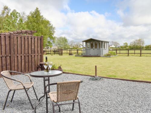 a patio with a table and chairs and a smallshed at The Willows in Hambleton