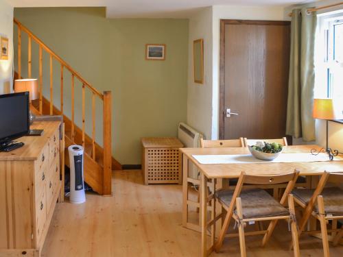 ein Wohnzimmer mit einem Holztisch und einem TV in der Unterkunft Willow Cottage in Newlyn East