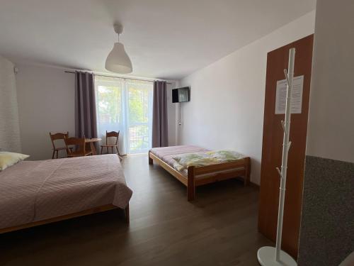 a bedroom with two beds and a table and chairs at Dom Gościnny Sówka in Pobierowo