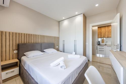 a bedroom with a large white bed and a kitchen at Olivia's Apartments in Velipojë