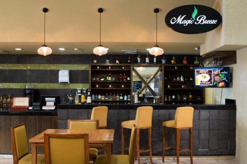a restaurant with a bar with yellow chairs and tables at Club Regina Cancun in Cancún