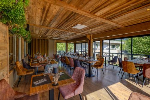 un restaurant avec des plafonds en bois, des tables et des chaises dans l'établissement Les Lodges du Lac, à Saint-Alban-de-Montbel
