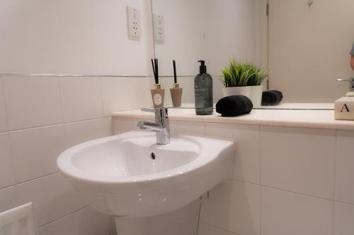 a white bathroom with a sink and a mirror at Elegant Retreat Carnoustie in Angus
