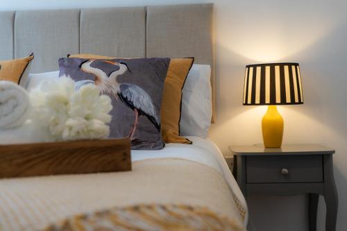 a bedroom with a bed with a bird pillow and a lamp at Elegant Retreat Carnoustie in Angus