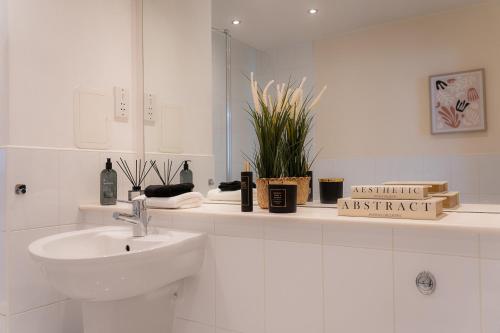 a white bathroom with a sink and a mirror at Elegant Retreat Carnoustie in Angus