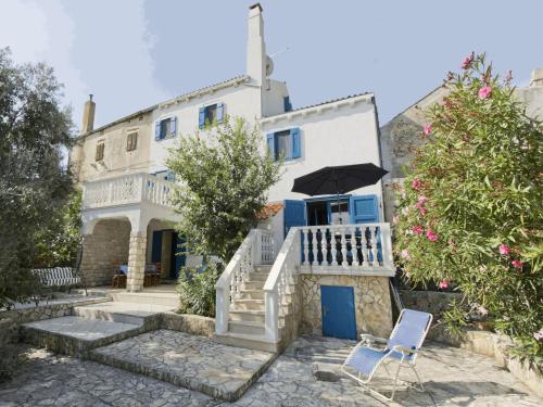 a white house with an umbrella and two chairs at Villa Karolina Großes Ferienhaus Meerblick 2000qm Garten Familien Gruppen Insel Lošinj in Nerezine