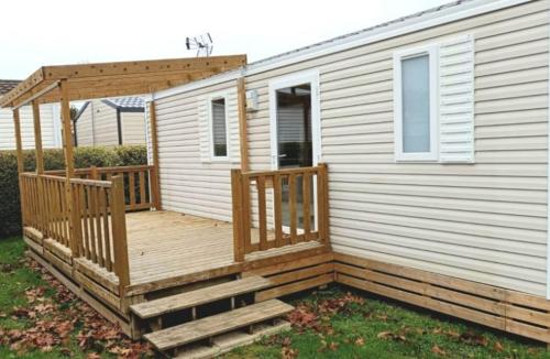 une terrasse en bois avec pergola sur une maison dans l'établissement Mobilhome avec terrasse couverte à 800 m de la plage, à Saint-Cast-le-Guildo