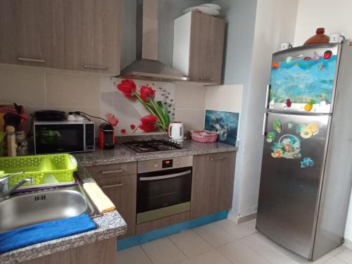 a kitchen with a stainless steel refrigerator and a sink at Appartement à Prestigia Plage des nations salé in Sale