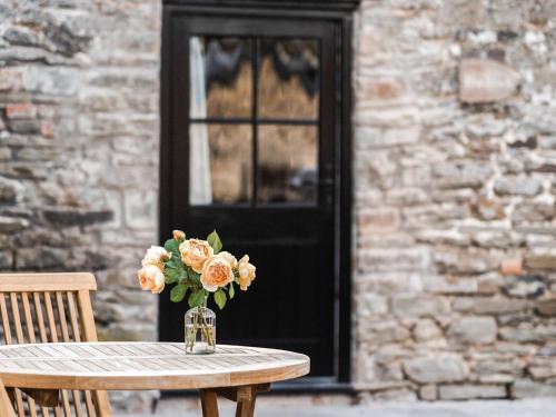 a vase of flowers sitting on a table in front of a door at Blackrock Barn in Clifford