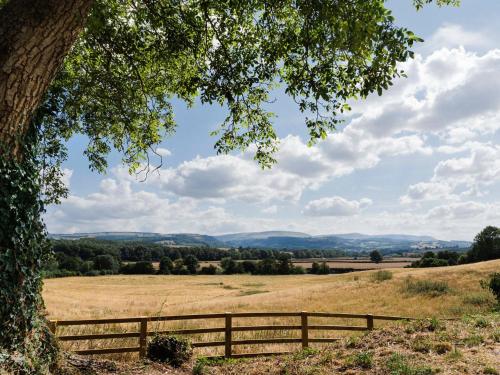 a field with a fence and a view of the mountains at Blackrock Barn in Clifford