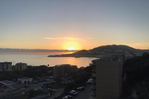 un coucher de soleil sur l'eau avec une ville et des bâtiments dans l'établissement Linda - Spacious 1Br Modern Terrace - by TGB, à Ajaccio