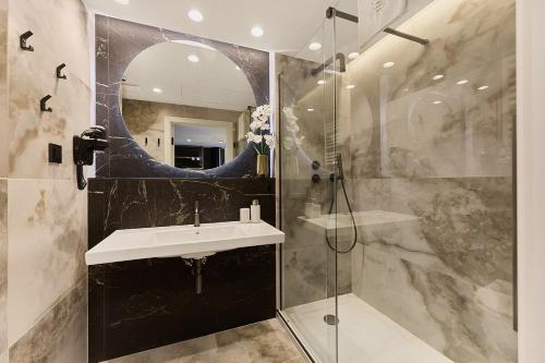 a bathroom with a sink and a shower with a mirror at Golden Hour Apartments- Loft H 214 in Świnoujście