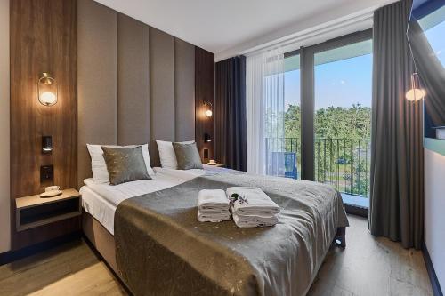 a bedroom with a large bed with two towels on it at Golden Hour Apartments- Loft H 214 in Świnoujście