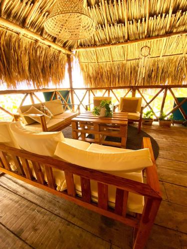 a room with couches and tables and a straw roof at Thani Ecobeach Barú in Playa Blanca