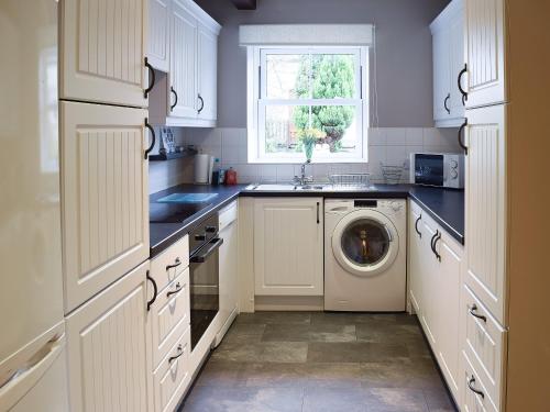 a white kitchen with a washer and a window at Manor Farm Cottage in Carperby