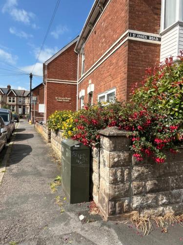 a brick building with flowers on the side of a street at St Anne's Road Guest House in Exeter