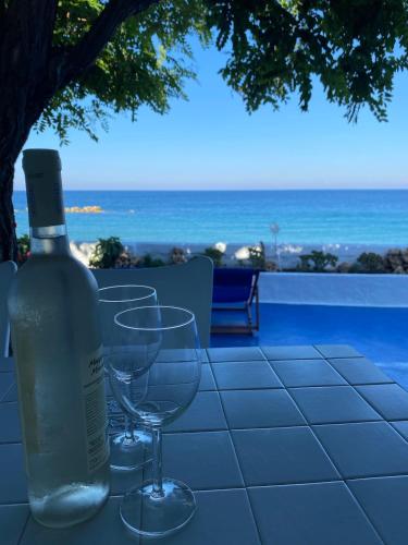 a bottle of wine sitting on a table with two wine glasses at House on the beach in Skiros