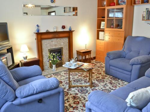 a living room with blue couches and a fireplace at Combe Cairn in Millom