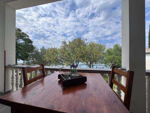 einen Holztisch auf einem Balkon mit Aussicht in der Unterkunft Apartments & Rooms Neno in Tribanj-Krušćica