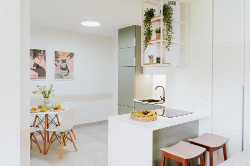 a kitchen with white walls and a counter with stools at Apartament 3A na ul Wiejskiej 32c in Oświęcim