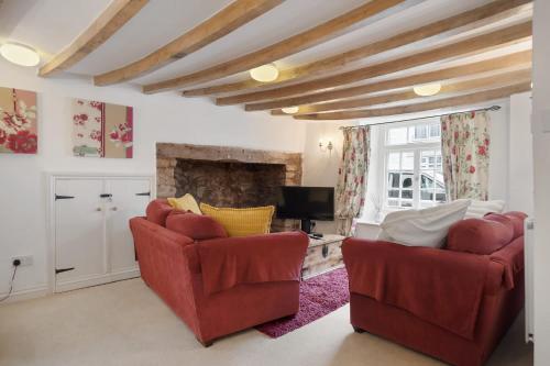 ein Wohnzimmer mit zwei Stühlen und einem Kamin in der Unterkunft Historic Cottage & Garden nr Quantock Hills in Nether Stowey
