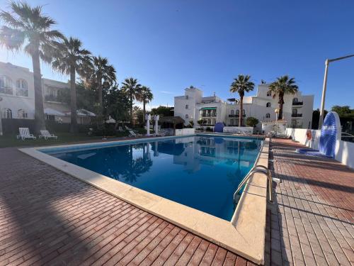 a swimming pool in a resort with palm trees at Green Apartment 14 in Tavira Garden in Tavira