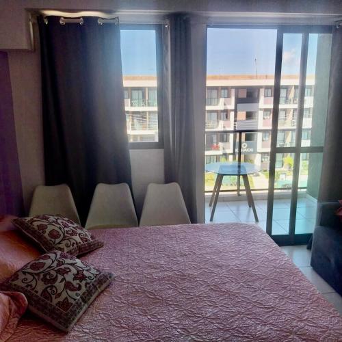 a bedroom with a bed and a large window at Flat em muro alto in Ipojuca
