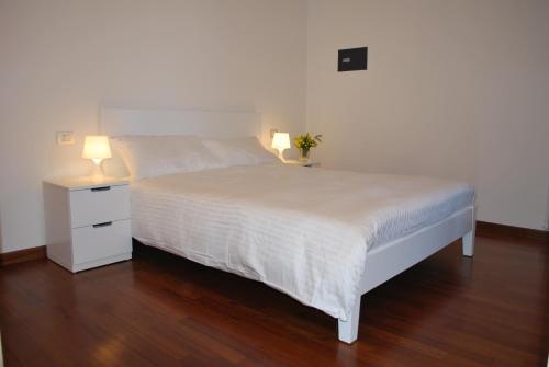 ヴェローナにあるLovely Apartment Veronaのベッドルーム(白いベッド1台、ランプ付きのナイトスタンド付)