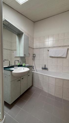 a bathroom with a sink and a tub and a mirror at Garden Park Apartment in Interlaken
