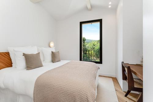 une chambre blanche avec un lit et une fenêtre dans l'établissement Maisons Amore Saint Tropez, à Saint-Tropez