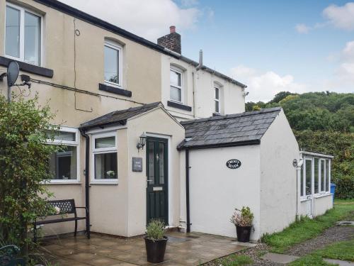 a white house with a black door at Cobb's Cottage in Grosmont