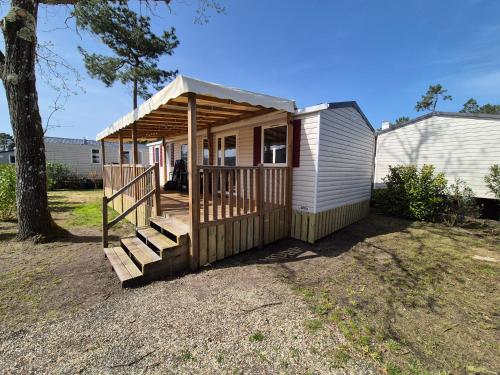une petite maison avec une terrasse couverte et des escaliers dans une cour dans l'établissement La cabane oceane, à Lège-Cap-Ferret